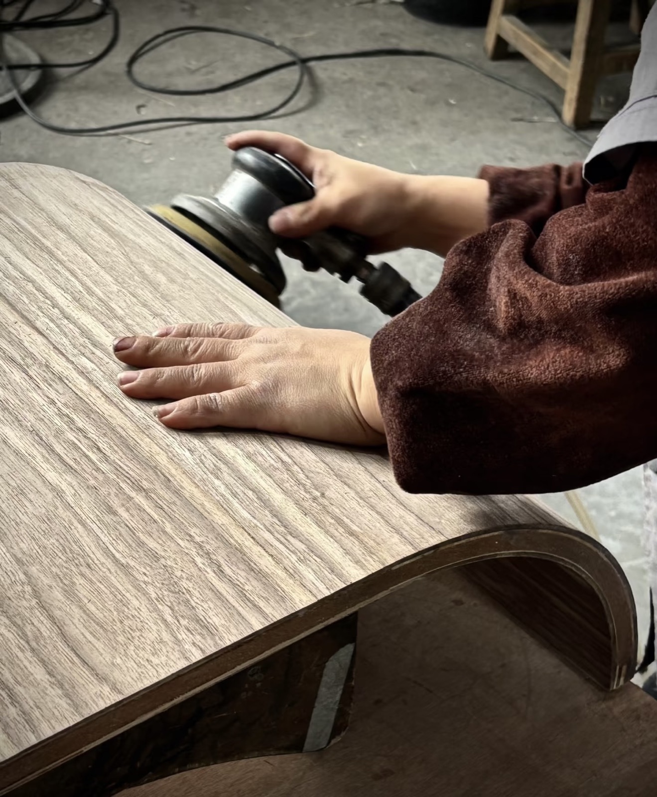 ponçage d'un plateau en bois courbé, fabrication en atelier — savoir-faire ayyur interiors.