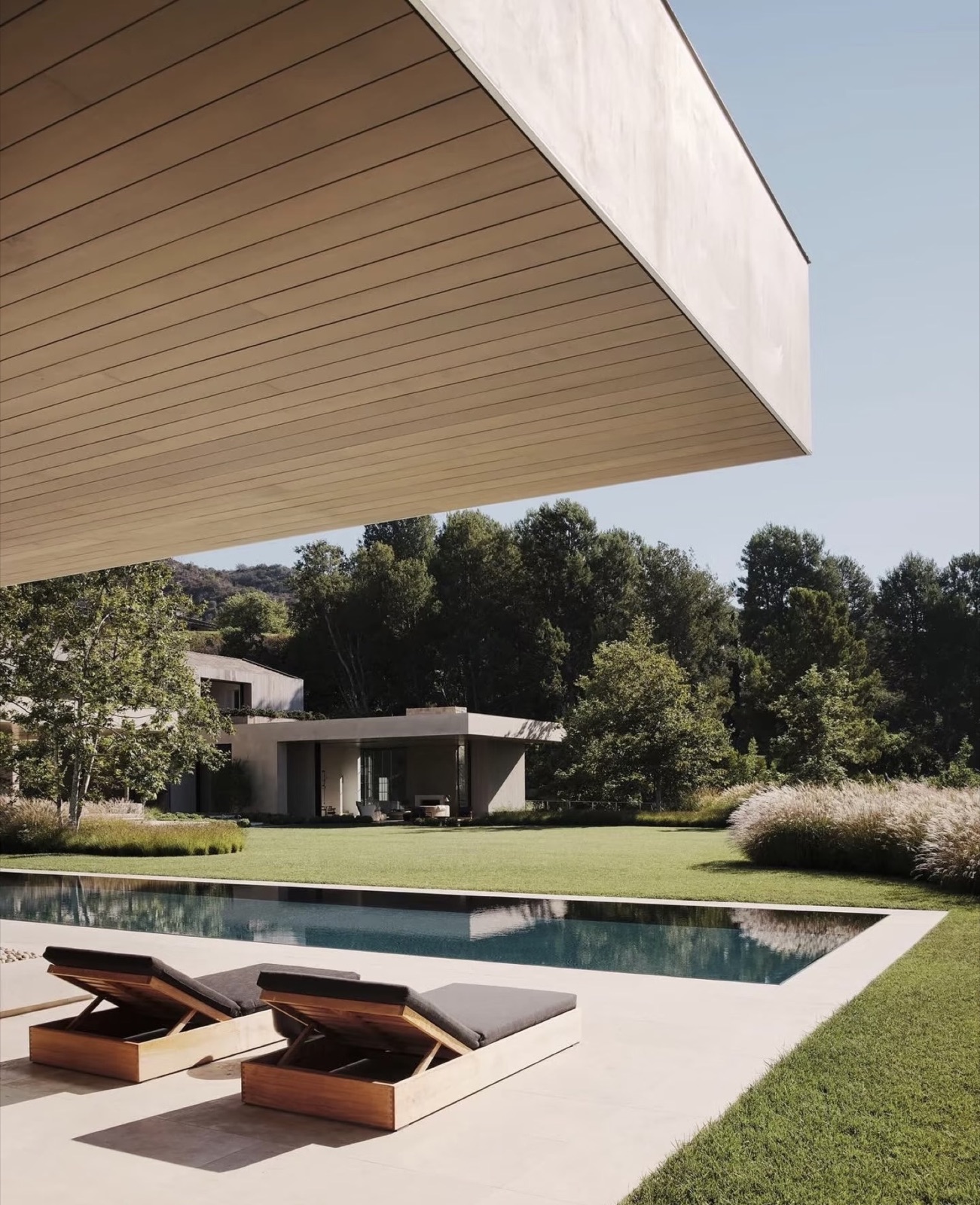 villa contemporaine, piscine à débordement et transats en bois — ayyur interiors.
